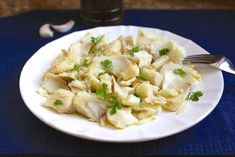 a white plate topped with pasta covered in sauce and garnished with parsley