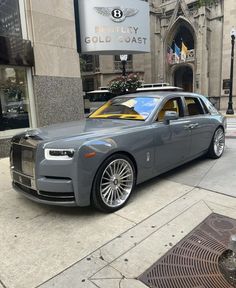 a grey rolls royce parked in front of a building