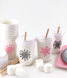 there are many cups and marshmallows next to each other on the table