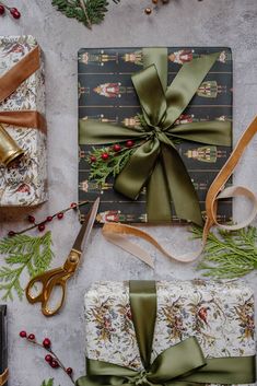 presents wrapped in wrapping paper and tied with green ribbon, surrounded by christmas greenery