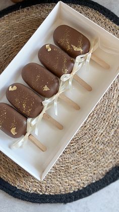 three chocolate covered pops in a white box