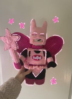 a person holding up a crocheted toy in the shape of a cartoon character