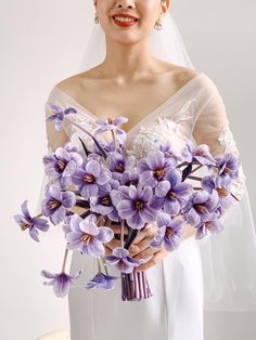 a bride holding a bouquet of purple flowers