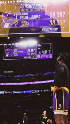 a basketball player standing in front of a scoreboard