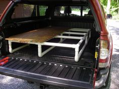 the back end of a red truck with a wooden table in it