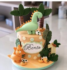 there is a cake decorated with dinosaurs and trees on the top of it, which reads denta