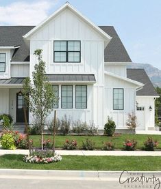 a large white house with lots of flowers in the front yard