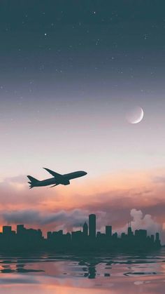 an airplane is flying over the city at sunset or dawn with a crescent in the sky