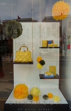 a window display with yellow flowers and purses in the front, along with other items