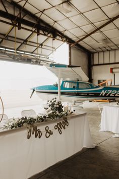 an airplane is parked in the hangar next to a table with flowers and candles on it