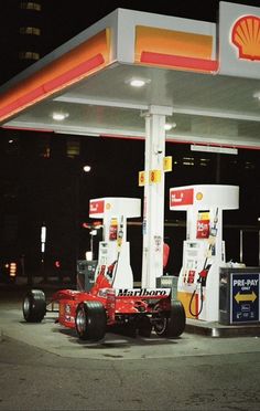 a gas station at night with cars parked in front of it and an oil pump on the side