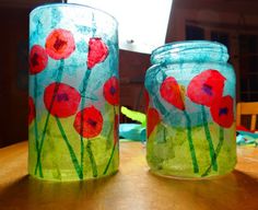 two glass jars sitting on top of a wooden table covered in red and green flowers