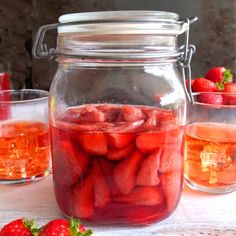 a jar filled with sliced strawberries next to two glasses full of water and ice