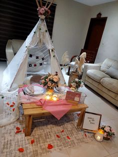 a small teepee tent is set up on the floor with candles and flowers around it