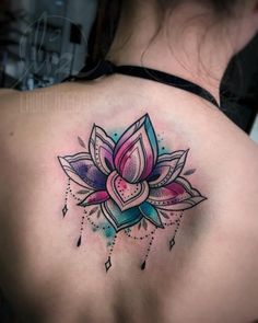 a woman's back with a colorful lotus tattoo on it