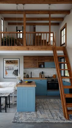 a kitchen with blue cabinets and stairs leading up to the loft above it's dining area