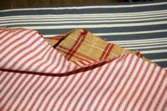 an unbuttoned red and white striped shirt laying on top of a bed