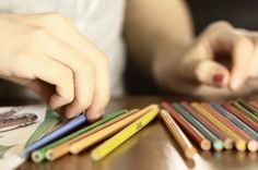 a person sitting at a table with many colored pencils in front of them and the words, fifi's school photo studio