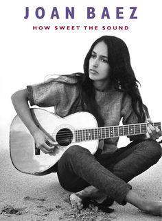 a woman sitting on the ground holding a guitar