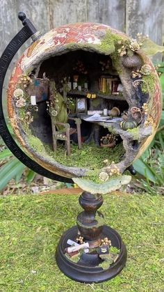 an old globe with moss growing out of it's sides in the grass near a fence