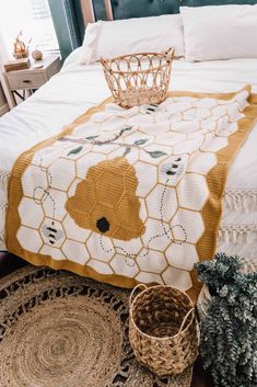 a bed covered in a yellow and white blanket next to two baskets on the floor