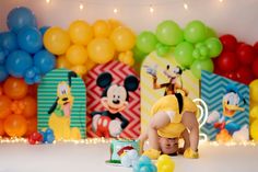 a little boy is playing with balloons in front of mickey mouses and other decorations