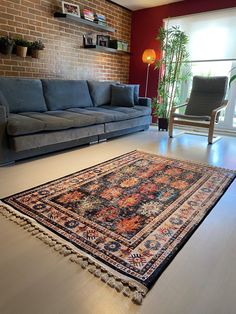 a living room with a couch, chair and rug on the floor in front of a brick wall