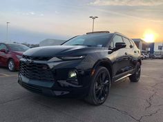 the front end of a black chevrolet suv in a parking lot with other cars behind it