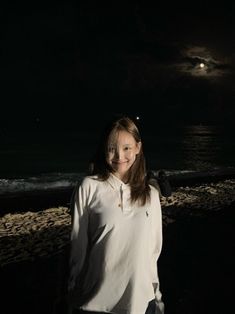 a woman standing on the beach at night