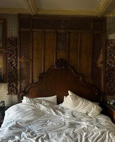 a bed with white sheets and pillows in a room that has wood paneling on the walls