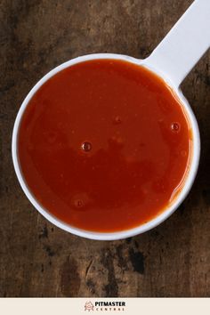 a spoon full of sauce sitting on top of a wooden table