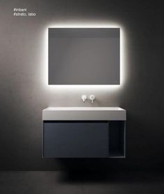 a bathroom with a sink, mirror and lights on the wall above it's counter