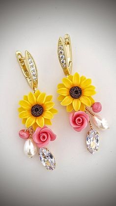 two yellow sunflowers with pink and white flowers are attached to gold ear clips