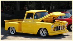 an old yellow pickup truck parked in a parking lot