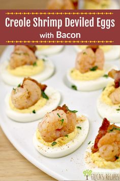 deviled eggs with shrimp and bacon on a white platter that is ready to be eaten