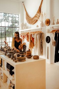 a woman sitting on top of a counter in a room filled with pots and pans