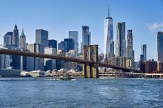 the skyline of new york city is seen from across the water in front of a bridge