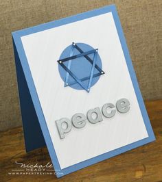 a blue and white card with the word peace written in silver on top of it