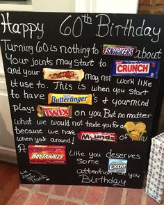 a birthday sign with candy bars on it and a gift box next to it that says happy 60th birthday