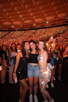 two women standing next to each other in front of a large crowd at a concert