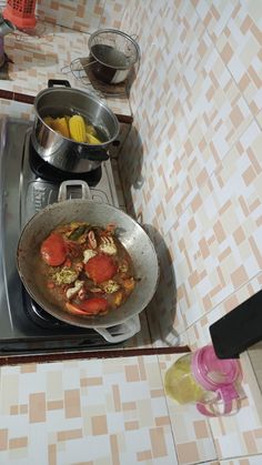 a stove top with some pans on it and food cooking in the skillet