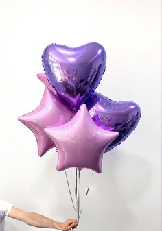 a person holding some purple balloons in their hand and the balloon is shaped like a heart