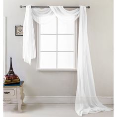 a white curtain hanging from the side of a window next to a table with an apple on it