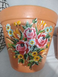 an orange flower pot with flowers painted on it