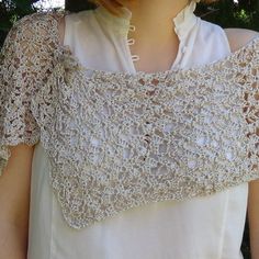 a close up of a woman wearing a white top with crochet on it