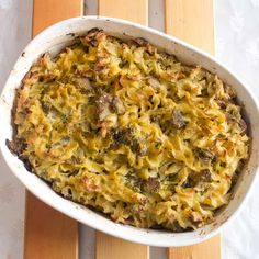 a casserole dish with broccoli and meat in it on a wooden table