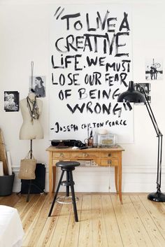 a wooden table sitting in front of a white wall with writing on the wall above it