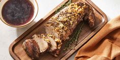 a sliced pork on a cutting board next to a bowl of sauce and a napkin