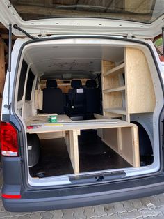 the back end of a van with its doors open and wooden shelves in the trunk