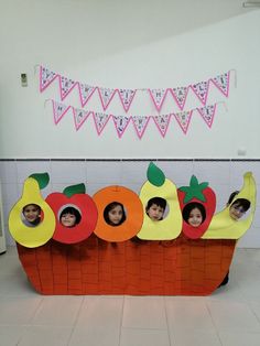 some kids are in a fruit basket made out of cardboard